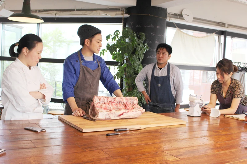 作業台に置かれた骨付きの牛肉を前に、参加者へ説明する藤田承紀